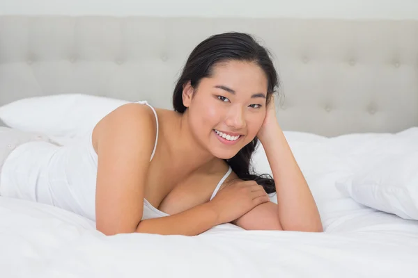 Lächelnde asiatische Frau liegt auf dem Bett — Stockfoto