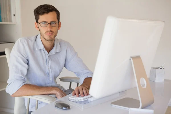 Casual affärsman rynkar på kameran vid sitt skrivbord — Stockfoto