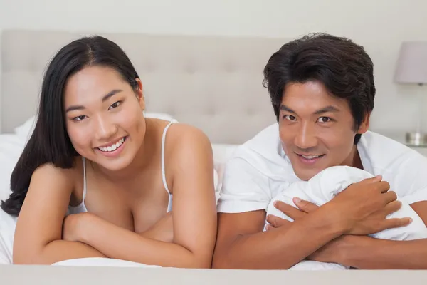 Happy couple lying on bed together — Stock Photo, Image