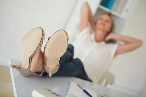 Mujer de negocios casual sentada en su escritorio con los pies en alto —  Fotos de Stock