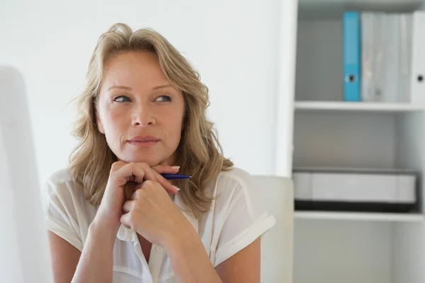 Casual businesswoman thinking at her desk — Stock Photo, Image