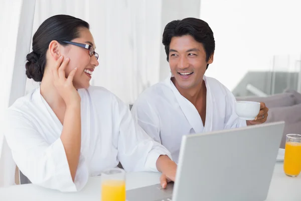 Par i badrockar spendera morgonen tillsammans med laptop — Stockfoto