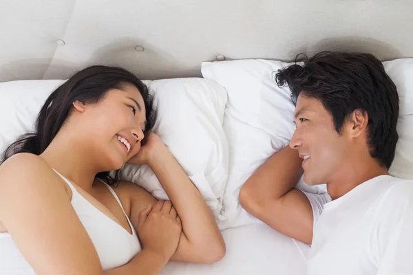 Lyckliga par liggande i sängen chattar — Stockfoto