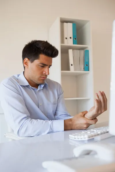 Hombre de negocios casual tocándose la muñeca adolorida — Foto de Stock