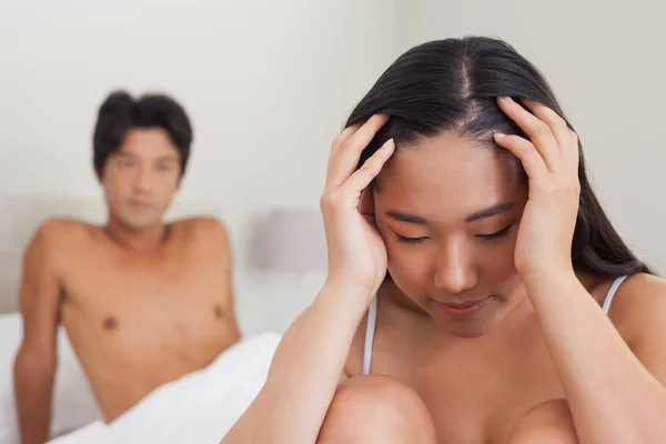 Boyfriend looking at upset girlfriend sitting on end of bed — Stock Photo, Image