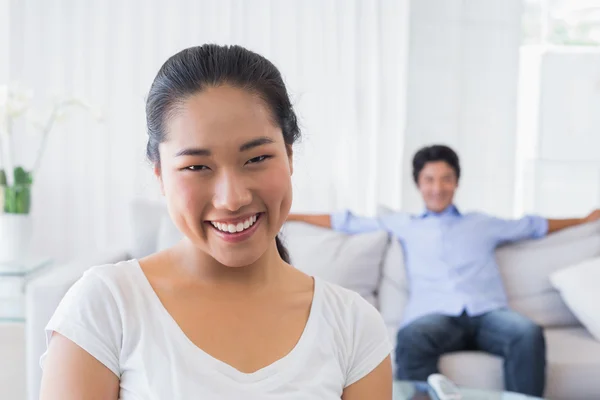 Happy woman smiling at camera with boyfriend in back — Stock Photo, Image