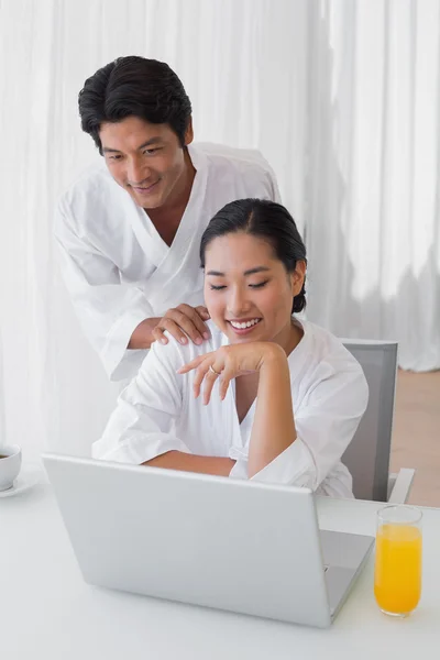 Par i badrockar med laptop tillsammans på morgonen — Stockfoto