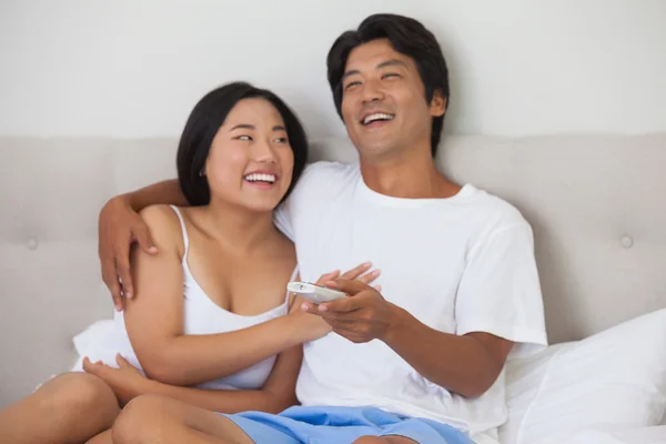 Happy couple lying on bed together watching tv — Stock Photo, Image