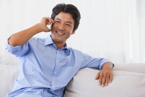 Happy man sitting on couch on the phone Royalty Free Stock Photos