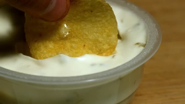 Рука макает чипсы в сливочный соус — стоковое видео