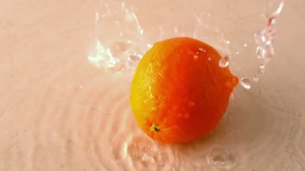 Апельсин вращается на мокрой белой поверхности — стоковое видео