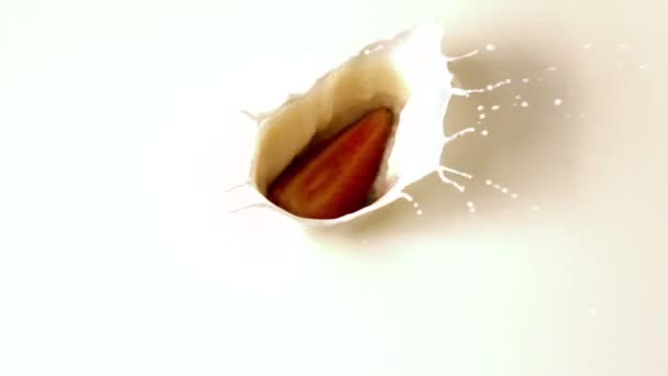 Клубника падает в стакан молока — стоковое видео