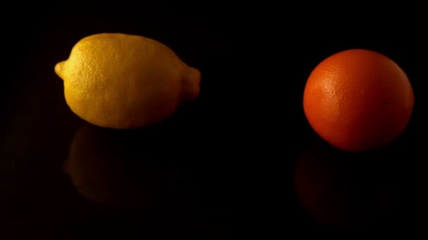 Lemon and orange spinning on black surface — Stock Video