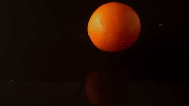 Апельсин падает на влажную поверхность — стоковое видео
