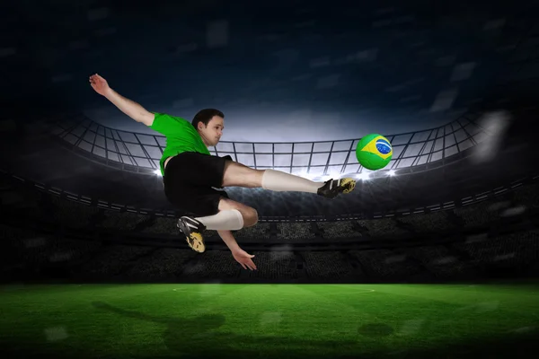 Composite image of football player in green kicking — Stock Photo, Image