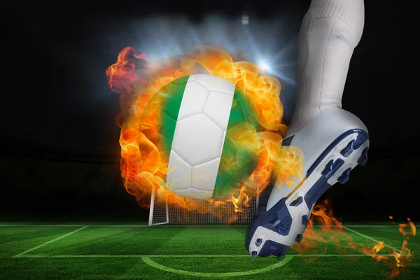 Jogador de futebol chutando bola de bandeira nigéria flamejante — Fotografia de Stock