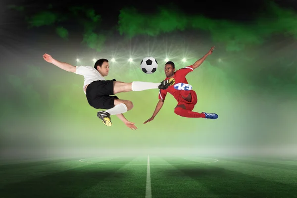 Composite image of football players tackling for the ball — Stock Photo, Image