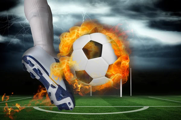 Football player kicking flaming ball — Stock Photo, Image