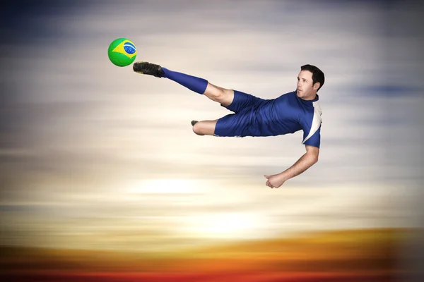 Composite image of football player in blue kicking — Stock Photo, Image