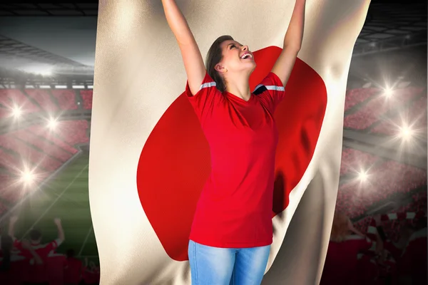 Zusammengesetztes Bild eines jubelnden Fußballfans in rot, der Japan fl hält — Stockfoto
