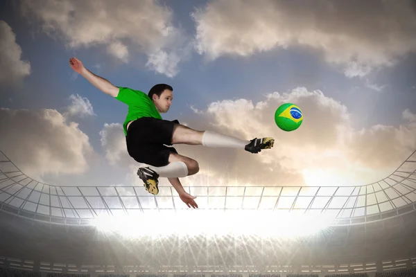 Imagen compuesta de jugador de fútbol en verde patadas — Foto de Stock