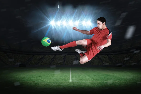 Imagen compuesta del jugador de fútbol en forma saltando y pateando — Foto de Stock