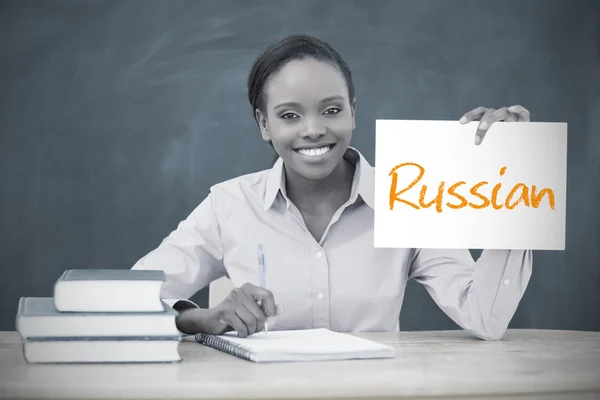 Happy teacher holding page showing russian — Stock Photo, Image