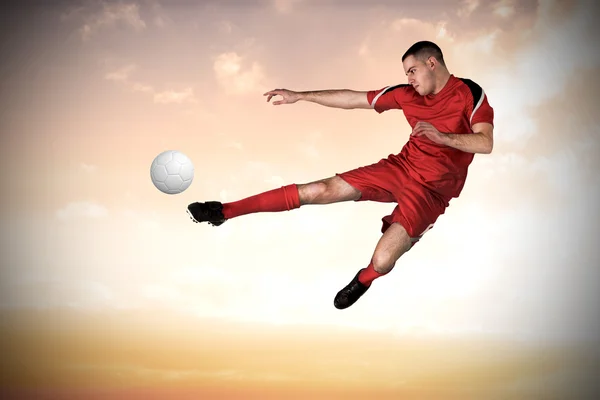 Imagen compuesta del jugador de fútbol en forma jugando y pateando —  Fotos de Stock