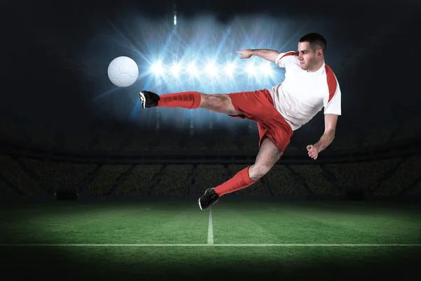 Composite image of fit football player playing and kicking — Stock Photo, Image