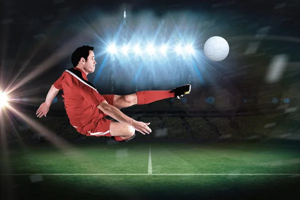 Bileşik görüntü kırmızı tekmeleme, futbolcu — Stok fotoğraf