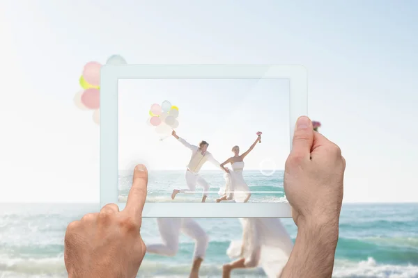 Hand holding tablet pc showing newlyweds — Stock Photo, Image