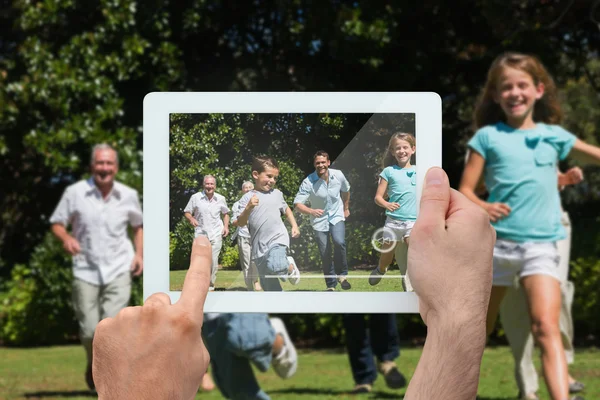 Rękę trzymając tablet pc wyścigi rodziny — Zdjęcie stockowe