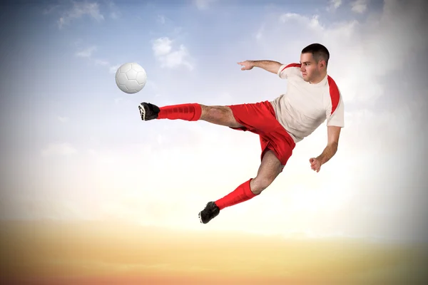 Composite image of fit football player playing and kicking — Stock Photo, Image