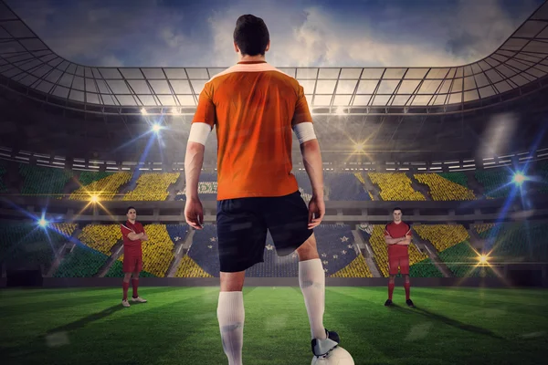 Jugador de fútbol en naranja con bola frente a la oposición — Foto de Stock