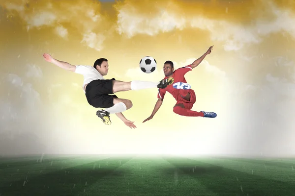 Composite image of football players tackling for the ball — Stock Photo, Image