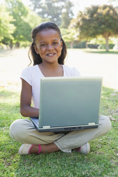 Flicka sitter på gräs med laptop — Stockfoto