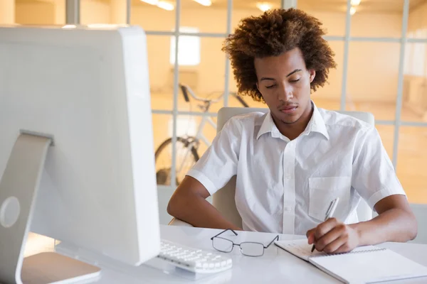 Geschäftsmann schreibt an seinem Schreibtisch — Stockfoto