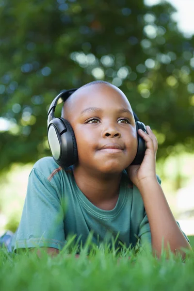 Boy lying on grass listening to music — Stock Photo, Image