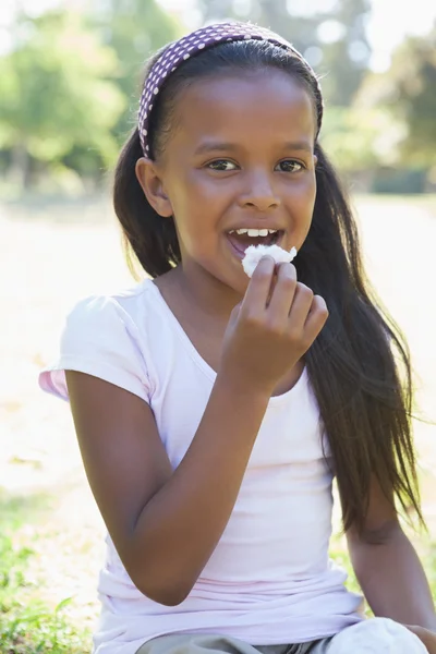 Mädchen sitzt auf Gras essen — Stockfoto