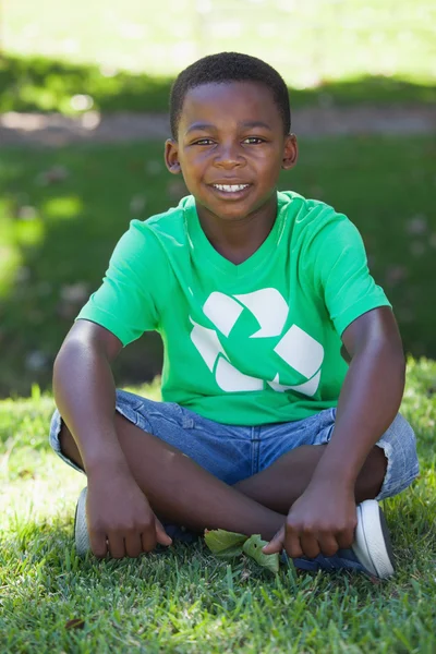 Мальчик сидит на траве в футболке — стоковое фото