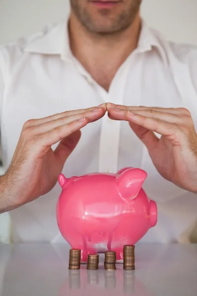 Zakenman sheltering piggy bank — Stockfoto