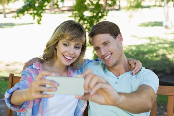 Pareja en el banco en el parque tomando una selfie — Foto de Stock