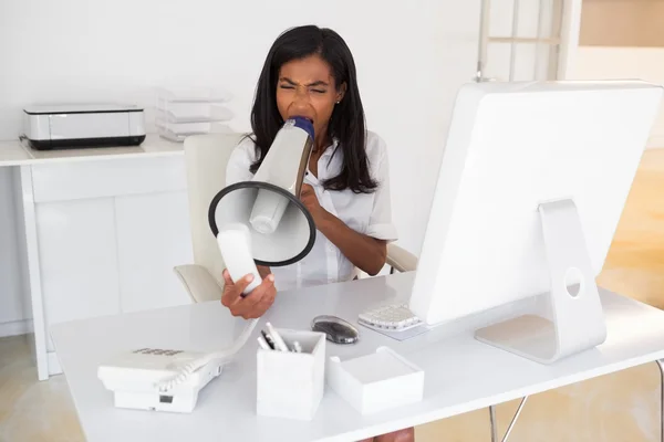 Businesswoman shouting in megaphone at phone — Stock Photo, Image