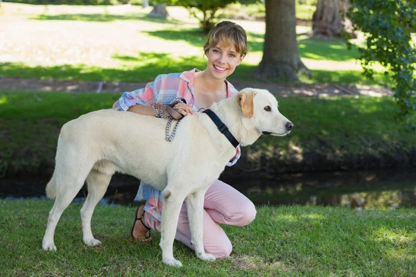 Blonde geknield met haar labrador in het park — Stockfoto