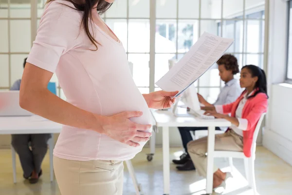 Pregnant office worker touches bump — Stock Photo, Image