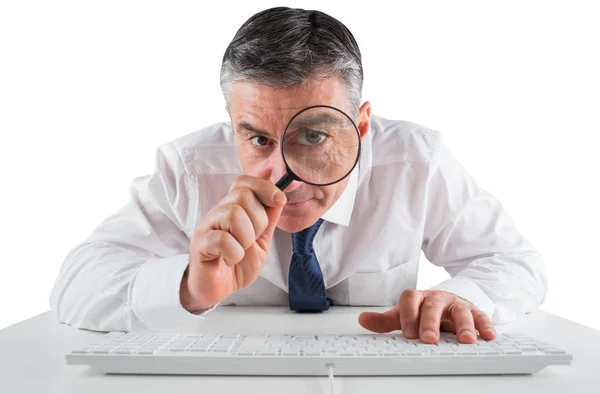 Mature businessman examining with magnifying glass Royalty Free Stock Images
