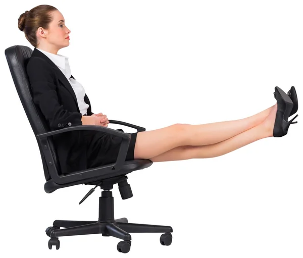 Kobieta siedzi na obrotowym fotelu z nogami — Zdjęcie stockowe