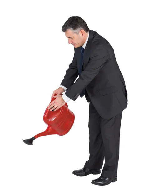 Mature businessman watering with red can — Stock Photo, Image