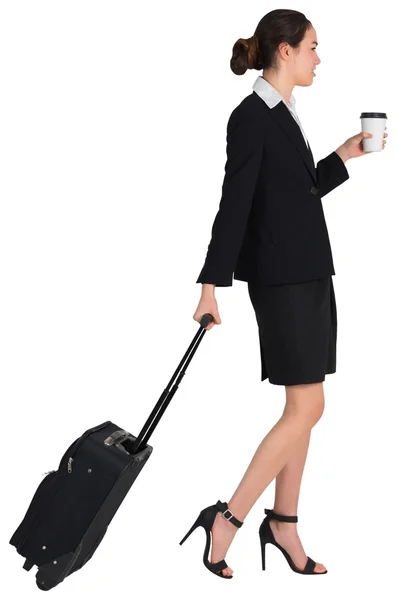 Businesswoman pulling her suitcase holding coffee — Stock Photo, Image