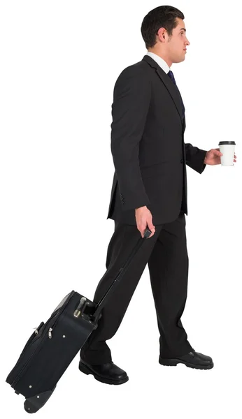 Businessman pulling his suitcase holding coffee — Stock Photo, Image